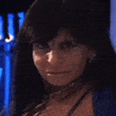 a close up of a woman wearing a blue jacket and a necklace