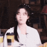 a young woman is sitting at a table with her eyes closed and a cup of coffee .