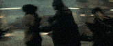 a group of people are standing next to each other in a dark room and fighting .
