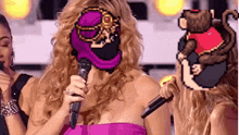 a woman in a pink dress is holding a microphone in front of her face while a monkey is behind her .