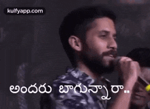 a man with a beard is holding a microphone in his hand and talking into it .