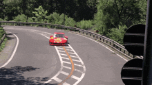 a red race car is going down a curvy road with a yellow sticker on the side that says ' ferrari '