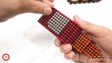 a person holding a bunch of red and silver beads with the words made in animatica on the bottom