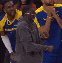 a man in a warriors jersey stands in the stands