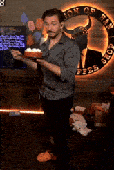 a man is holding a cake in front of a sign that says son of hammer shop