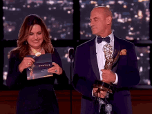 a woman holding a card that says emmys next to a man