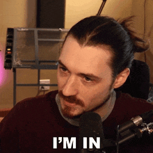 a man sitting in front of a microphone with the words i 'm in on his face