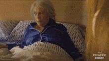an older woman is laying in bed with a disney freakier friday ad behind her