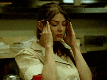a woman with a pencil in her hair holds her hands to her head