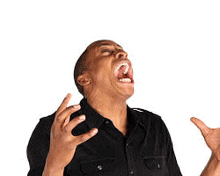 a man in a black shirt is making a funny face with his mouth open and his hands in the air .