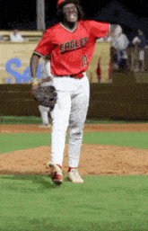 a baseball player wearing a red eagles jersey is standing on the field