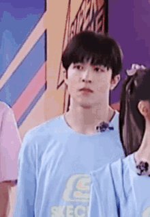 a young man in a blue shirt is standing next to a girl in a pink shirt .