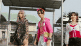 three women are standing next to each other and one has pink hair