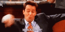 a man in a suit and tie is sitting on a couch and saying whoop ah .