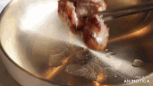 a piece of meat is being stirred in a pan with chopsticks and the words made in animatica visible in the corner