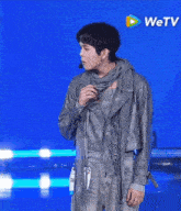 a man in a leather jacket is standing in front of a blue background with a wetv logo in the corner