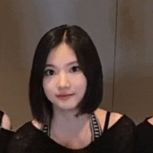 a young woman with short black hair is wearing a black tank top and a black shirt .
