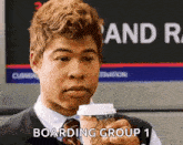 a man in a suit and tie is holding a cup of coffee and saying boarding group 1