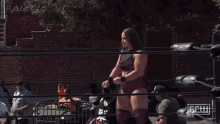 a female wrestler in a purple outfit is standing in a ring with a sign that says getw