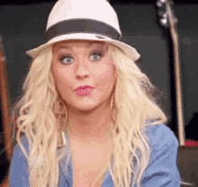 a woman wearing a white hat and a blue shirt is making a funny face .