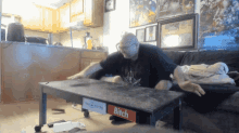 a man is sitting on a couch with a bitch sign on the table