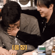 a man is holding another man 's neck with a yellow sticker that says ' yong ' on it