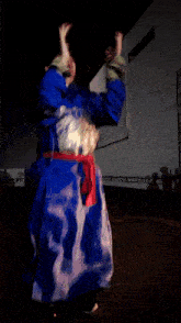 a man in a blue robe with a red sash around his waist