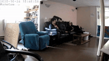 two people sit on a couch in a living room with the time of 15:45