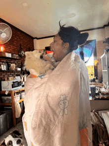 a woman is holding a dog wrapped in a blanket with a rabbit on it