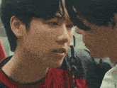 a man in a red shirt kisses another man on the cheek