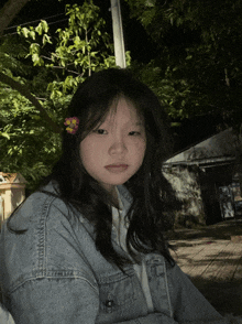 a girl with a flower in her hair is wearing a blue denim jacket