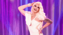 a drag queen is wearing a white dress and pearls while dancing on a stage .
