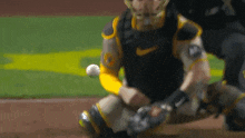 a baseball player wearing a nike uniform is kneeling on the field catching a ball .