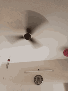 a ceiling fan is spinning in a room with a red balloon hanging from the ceiling