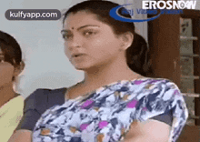 a woman in a saree is standing next to another woman in a room and making a funny face .