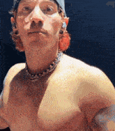a shirtless man is wearing a hat and a necklace