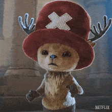 a stuffed animal wearing a red hat with an x on it and antlers