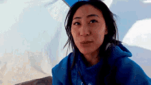 a woman wearing a blue hoodie is sitting in front of a tent .