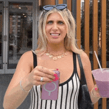 a woman in a striped tank top holds a purple smoothie