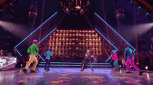 a group of people are dancing in front of a disco ball
