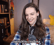a woman wearing ear buds and a plaid shirt with the words twitch.tv/itstina above her