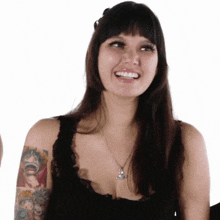 a woman with a tattoo on her arm is smiling and wearing a necklace