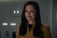a woman wearing a yellow jacket and black shirt smiles at the camera