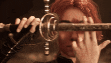 a close up of a person holding a sword in front of their face