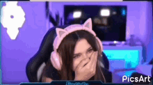 a woman wearing headphones and cat ears is laughing while sitting in a chair .