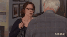 a woman with glasses is talking to an older man with peacock written on the bottom