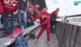 a young boy wearing a ferrari sweatshirt stands in front of a crowd of people