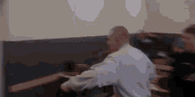 a man is sitting at a table with his arms outstretched .