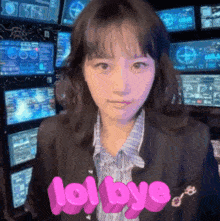 a girl in front of a wall of monitors with lol bye written in pink letters