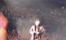 a man is singing into a microphone in front of a crowd .